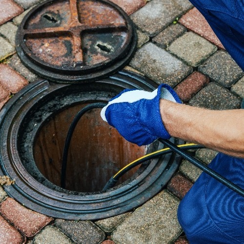 A Plumber Cleans a Sewer Pipe.