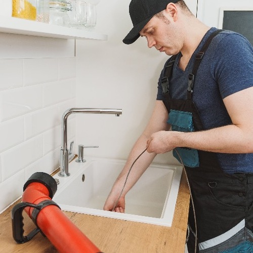 plumber using a drain snake for a clog